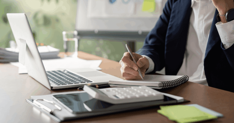 Profissional analisando dados financeiros em um escritório com notebook, calculadora e anotações, representando o uso da tabela ICMS para cálculos tributários.
