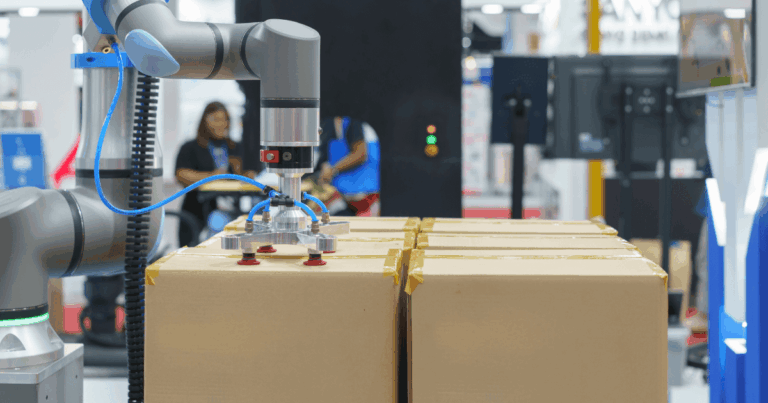 Robô industrial realizando operação de pick and place para movimentação e organização automática de caixas de papelão em linha de produção moderna.