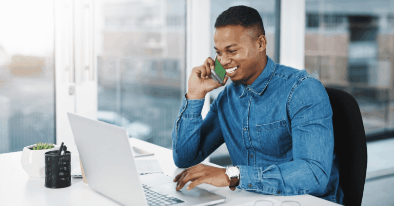 Vendedor sorridente realizando atendimento por telefone em home office, exemplificando estratégias de inside sales com uso de notebook e ferramentas digitais.
