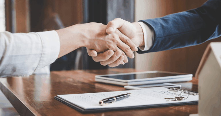 Imagem de duas pessoas firmando um acordo com um aperto de mãos, simbolizando a assinatura de contratos, como os Master Service Agreements, em um ambiente de negócios formal.