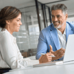 Profissionais do backoffice em reunião corporativa, analisando informações estratégicas no computador em ambiente de escritório moderno.