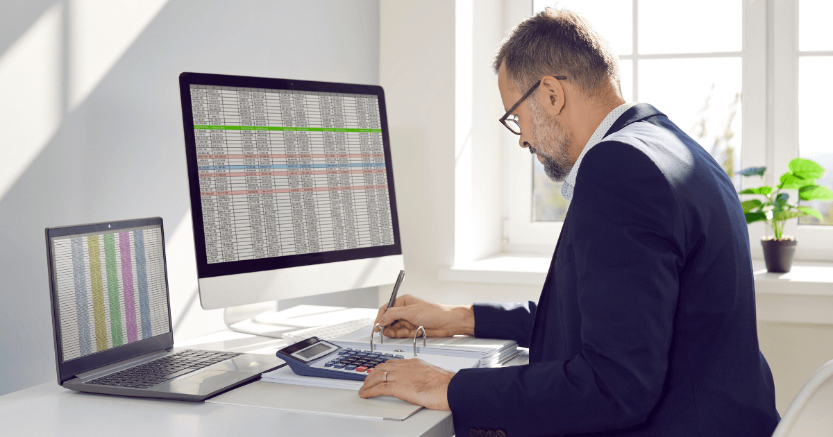 Profissional analisando planilhas e dados financeiros no computador, representando o impacto da carga tributária na gestão empresarial.
