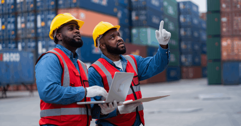 Profissionais de logística analisando containers em porto, representando o papel do freight forwarder na gestão eficiente da cadeia internacional com apoio de ERP.