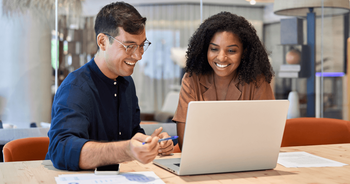 Profissionais trocando ideias em frente ao notebook, simbolizando a aplicação do funil de ideias para estimular criatividade e inovação nos negócios.