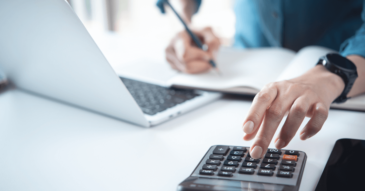 Profissional calculando impostos com notebook e calculadora, representando a apuração e controle do ICMS ST na rotina fiscal das empresas.