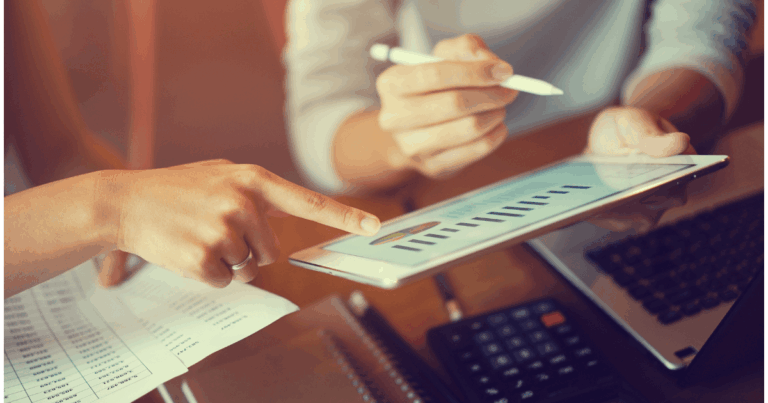 Profissionais analisando gráfico em tablet com indicadores de desempenho, representando a mensuração de KPIs de vendas para tomada de decisões estratégicas.